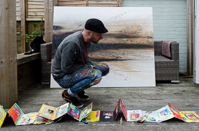 My Dog Sighs in his patio, in front of one of his last canvasses, with one of his sketchbooks spread on the floor