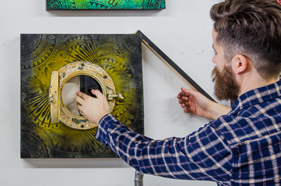 Beau Stanton installing an Ipad playing an animation  of his work inside an ornamented porthole